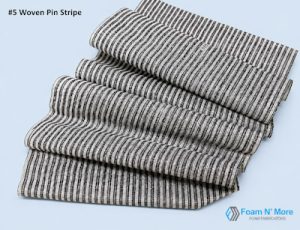 Draped pin stripe fabric with black and white vertical stripes, on a gray background. The fabric appears slightly textured and of lightweight to medium weight.