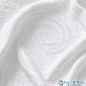 Close-up of white Tencel mattress cover fabric featuring an embossed swirl pattern with a soft, draped appearance that highlights the texture and quilted design.